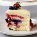 A slice of Chantilly cake with berries.