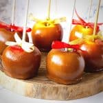 Caramel coated apples on a wooden board.