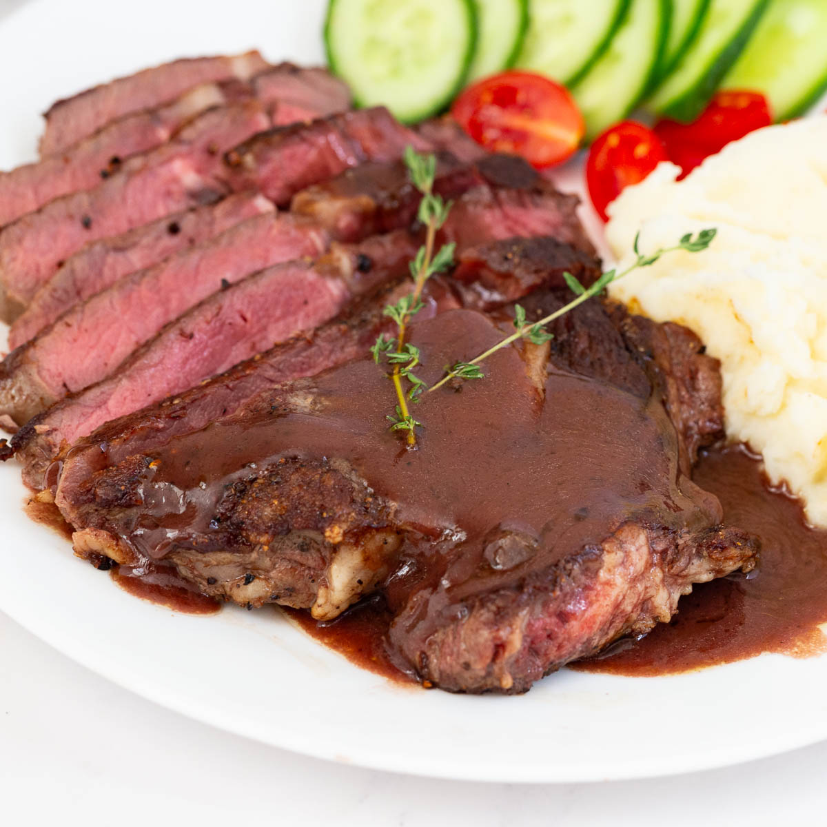 A white plate with red wine deglazed pan steak sauce.