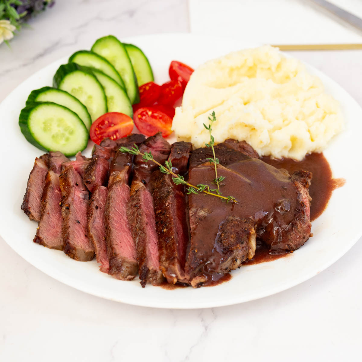 A white plate featuring red wine sauce for steak served with mashed potatoes.