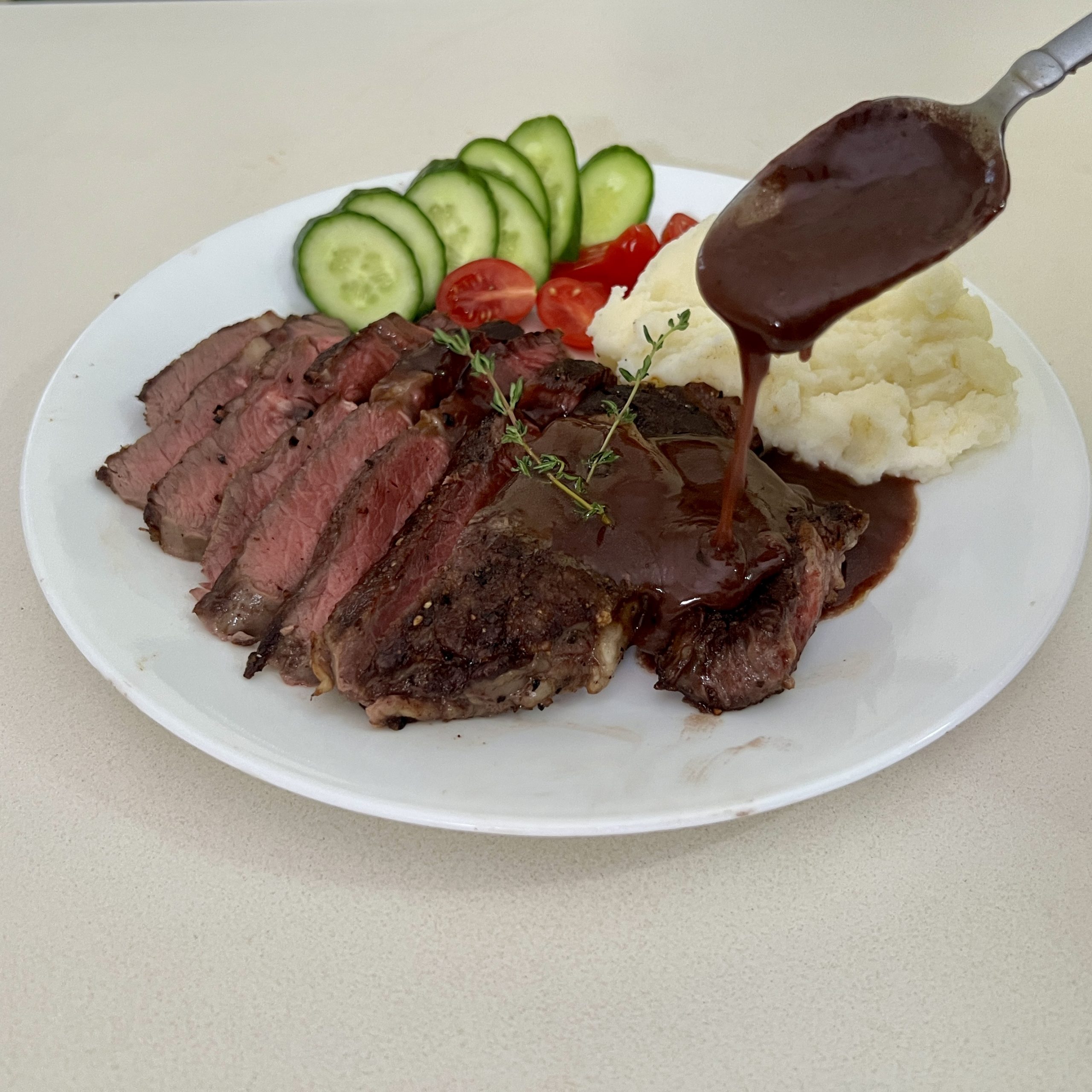 White plate with steak pan sauce over steak.