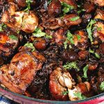 A skillet with chicken and chestnuts.