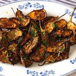A white platter with baby roasted eggplant.
