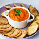 A plate with crackers and crostini and romesco.