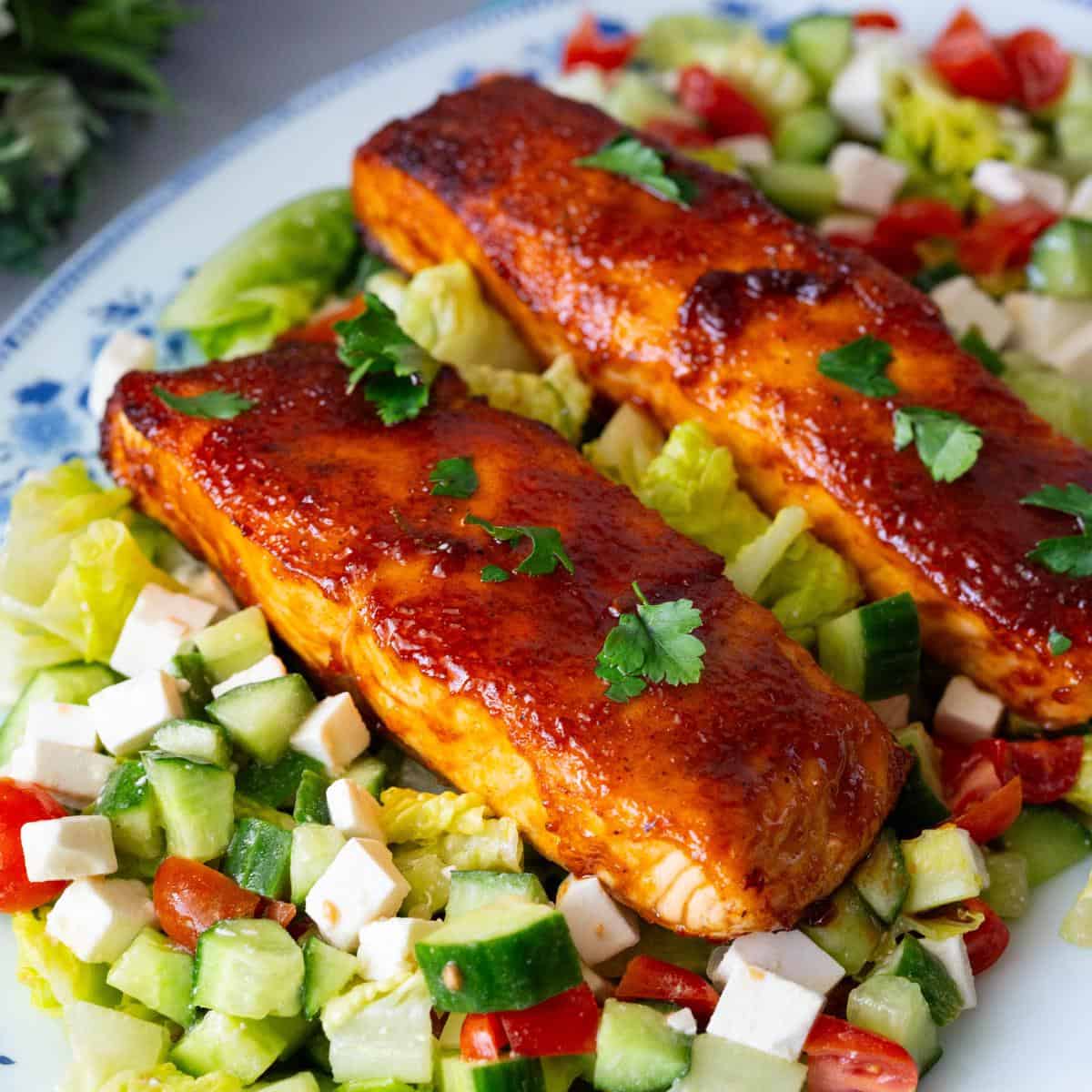 A large platter with BBQ salmon over salad.