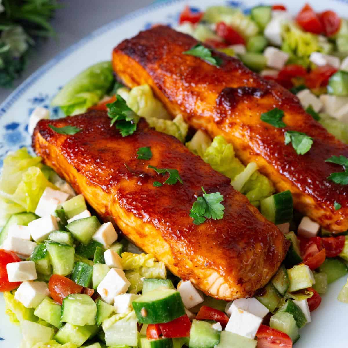 A platter with BBQ salmon over salad.