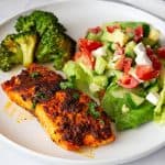 A plate with salmon fillet and salad.