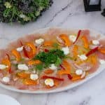 A large platter of carpaccio with tuna in dressing.