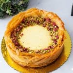 A baked baklava cheesecake on a cake stand.
