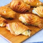 A wooden board with filo bites made with swiss chard and kale.