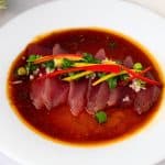 A white plate with tuna slices with ponju sauce.