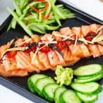 A black ceramic plate with salmon sashimi.