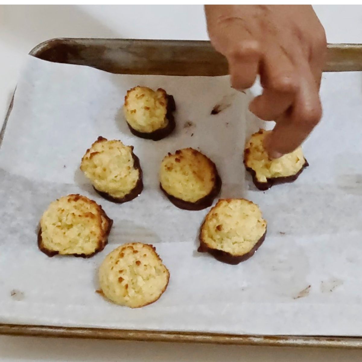 Dipping macarons in chocolate.