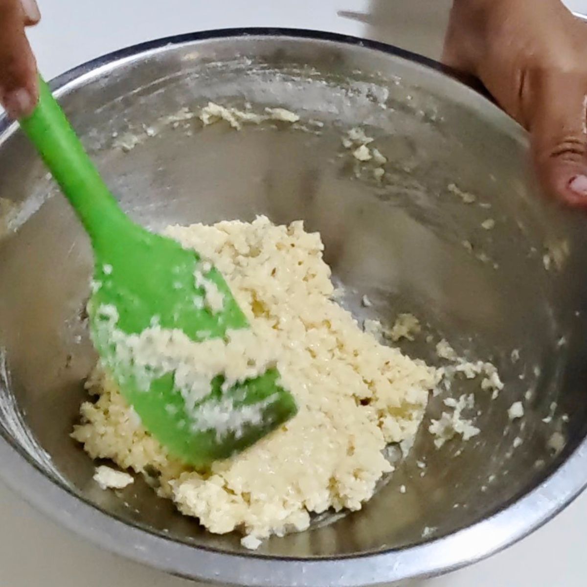 Coconut macaroon cookie batter in a stainless bowl.