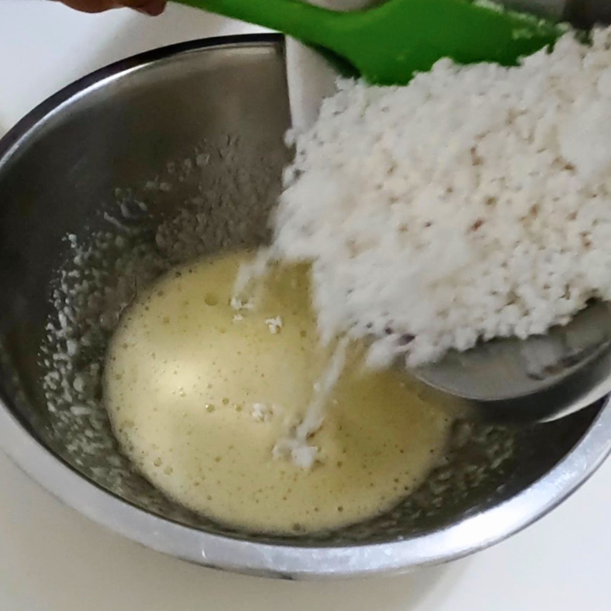 Adding fresh coconut to the macaroons cookie batter.