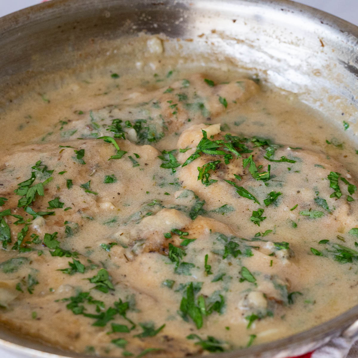 A frying pan with chicken cutlet.