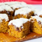 A wooden board with frosted pumpkin cake slices.