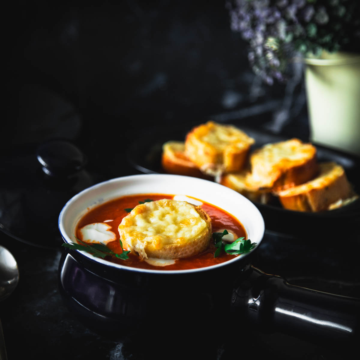 Red pepper and tomato soup in a blue bowl.