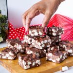 A hand stacking fudge on the table.