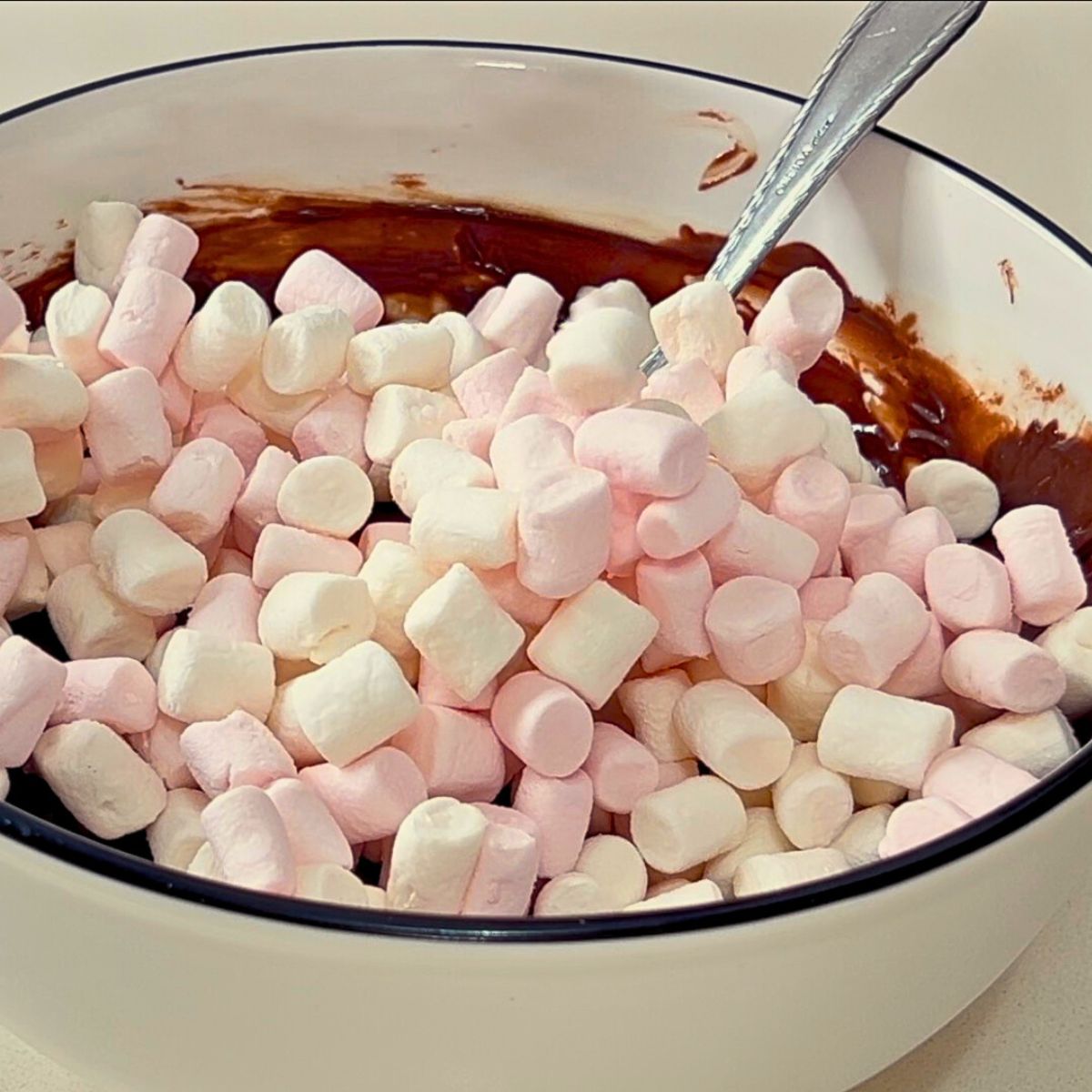 A white bowl with marshmallows and fudge mixture.