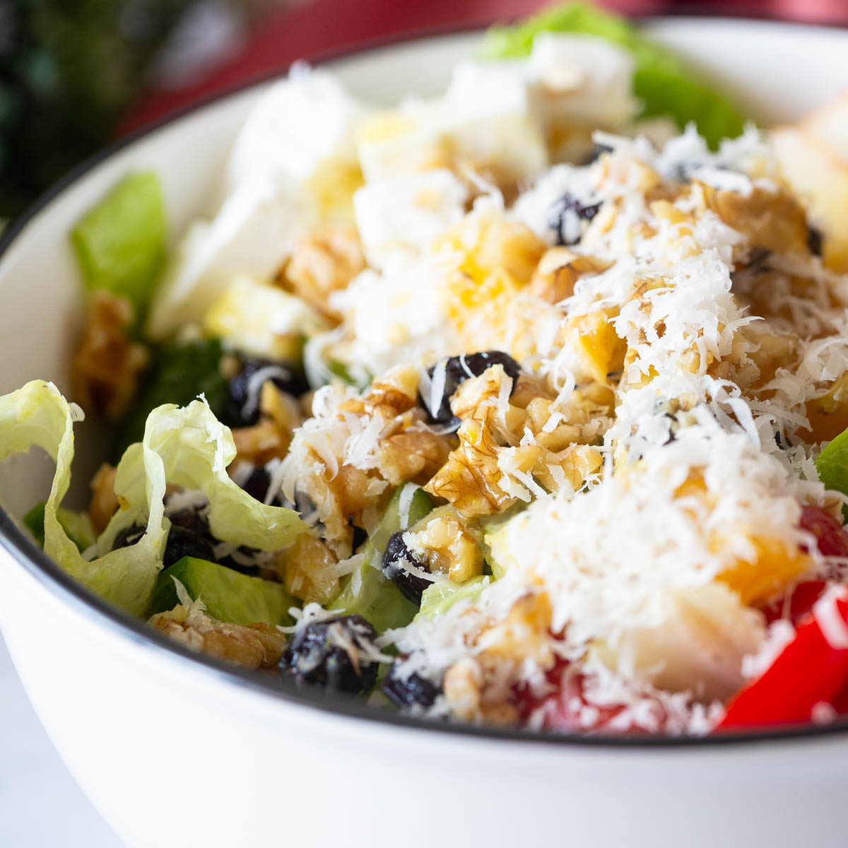 A white bowl with salad and parmesan cheese.