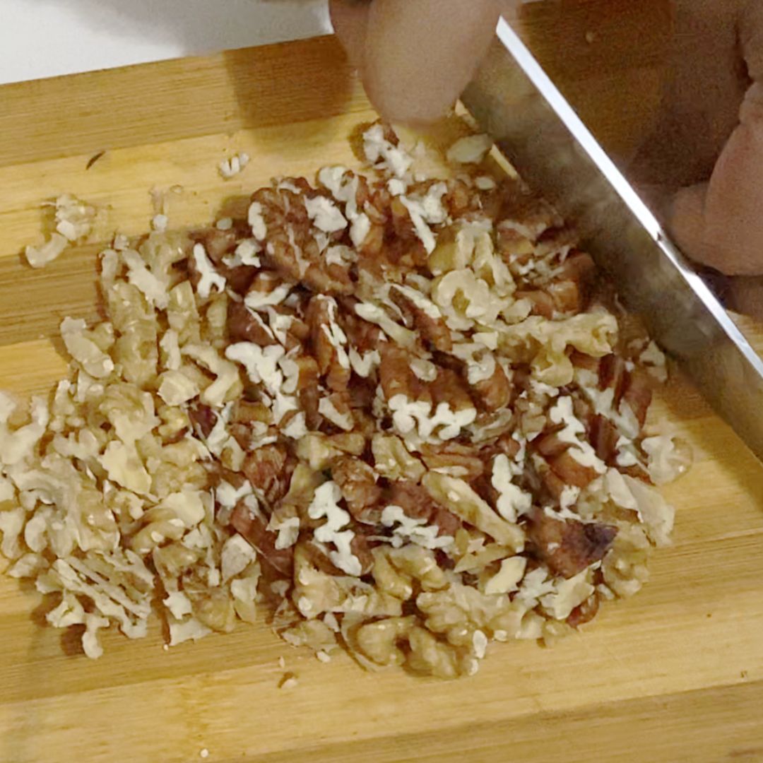 Chopping pecans on a wooden cutting board.