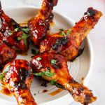 A white plate with BBQ chicken legs.