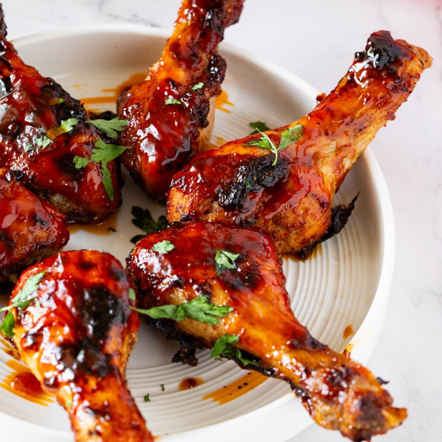 A white plate with BBQ chicken legs.
