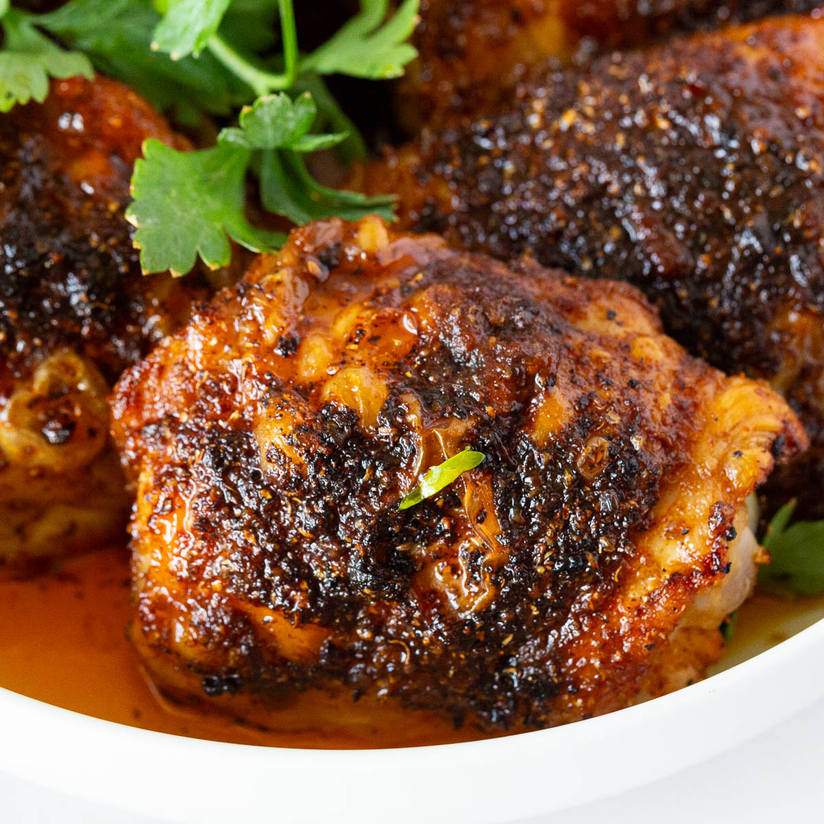A white plate with chicken thighs.