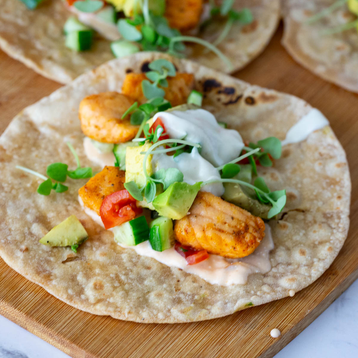 Salmon tacos with veggies on the table.