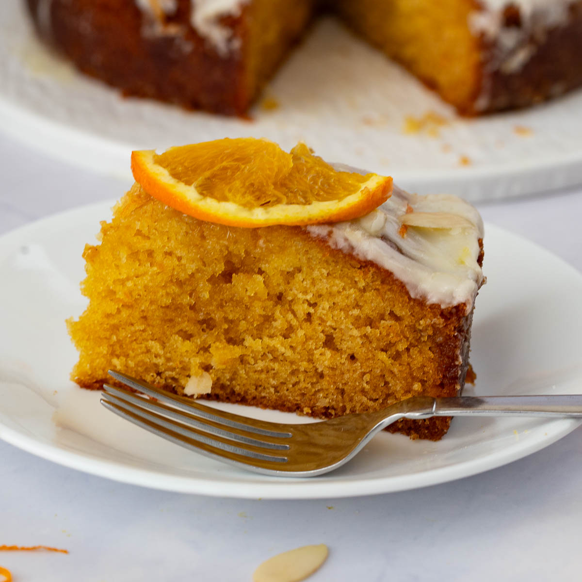 A slice of orange cake on a saucer.