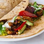 A white plate with chicken fajitas.