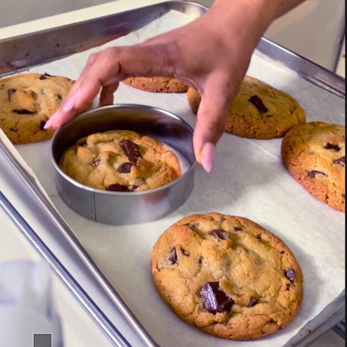 A sheet tray with fresh baked cookies and a cookie cutter.