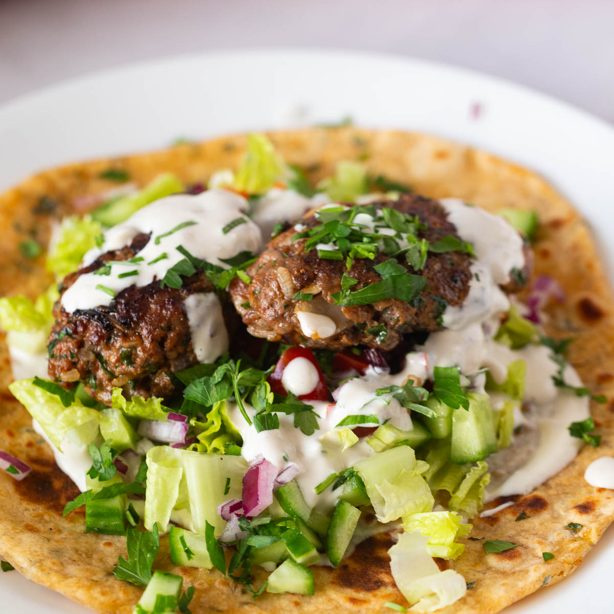 A flatbread with kofta kebabs and salad.
