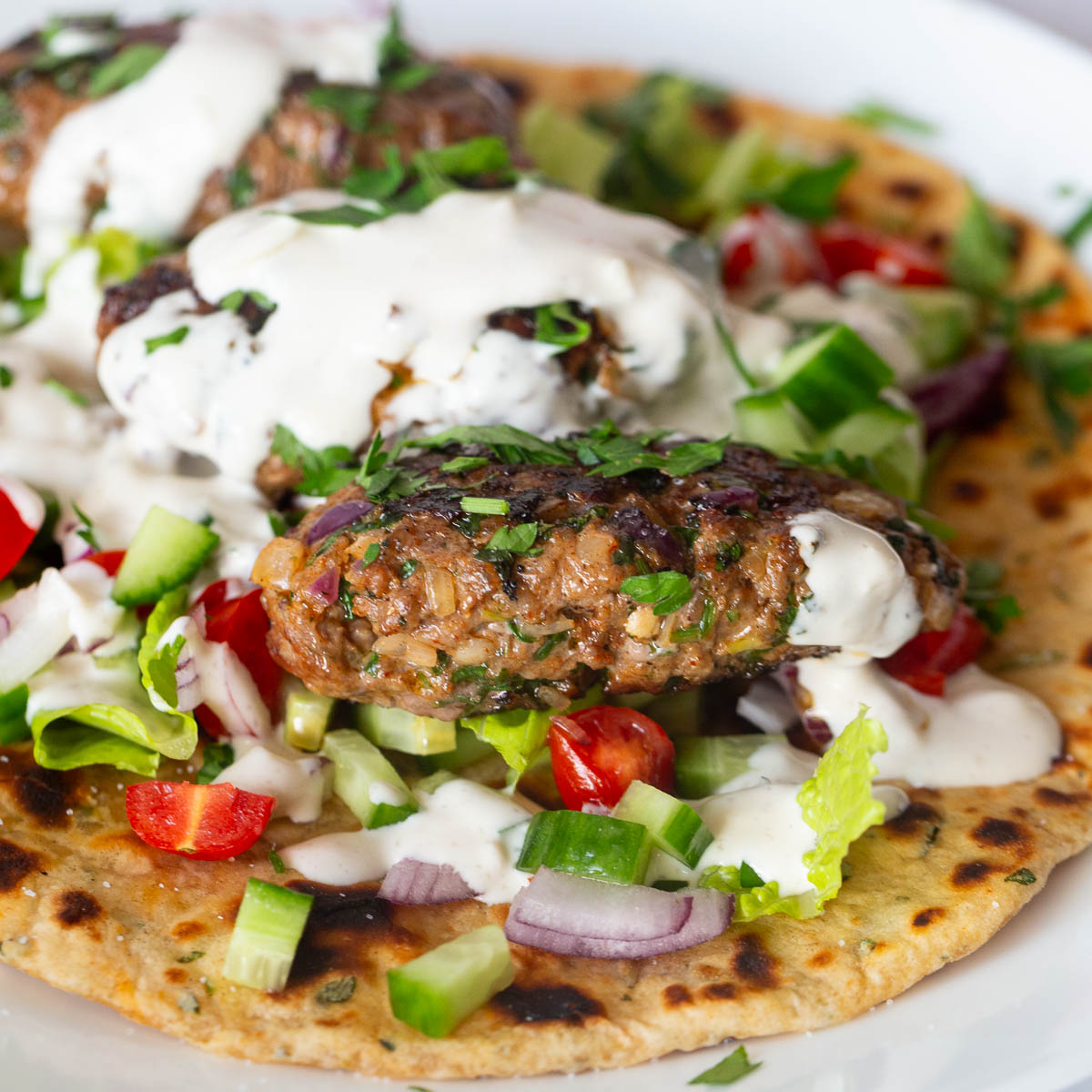 A flatbread with kofta kebabs with salad.