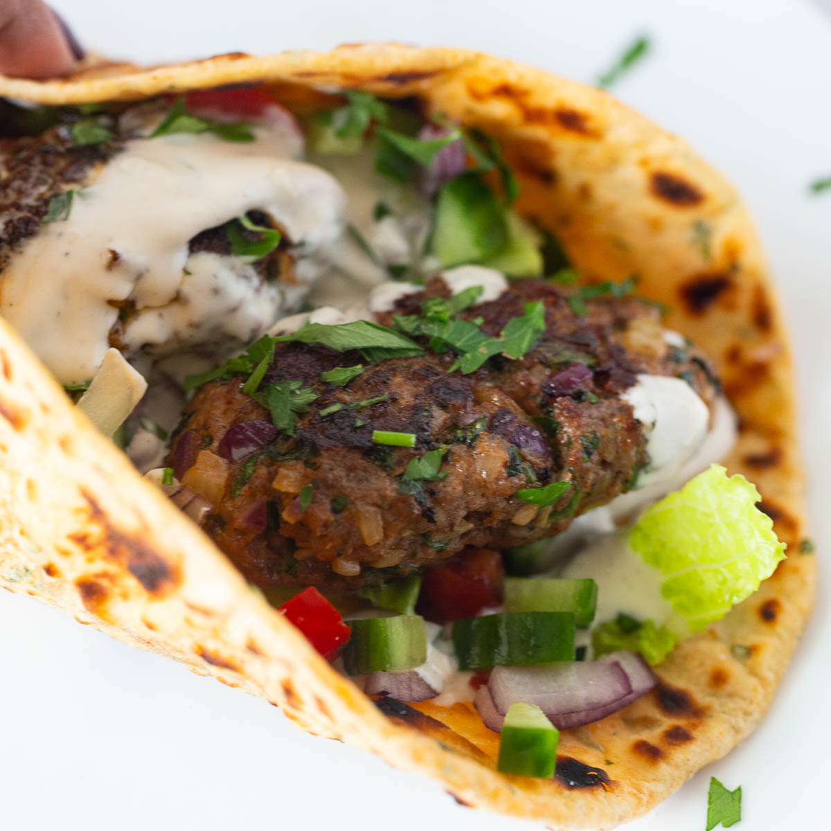A flatbread with kebabs and salad.