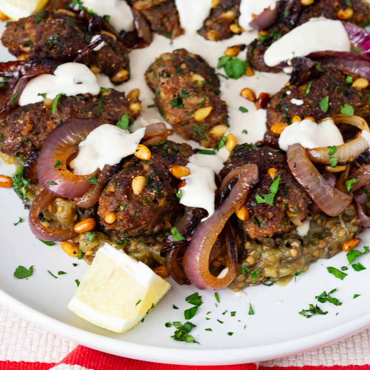 A platter with eggplant puree and beef kebabs.