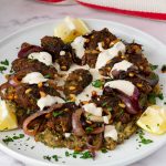 A platter with roast eggplant and kebabs.
