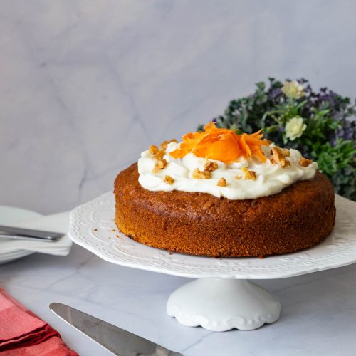 A frosted carrot cake on the cake stand.