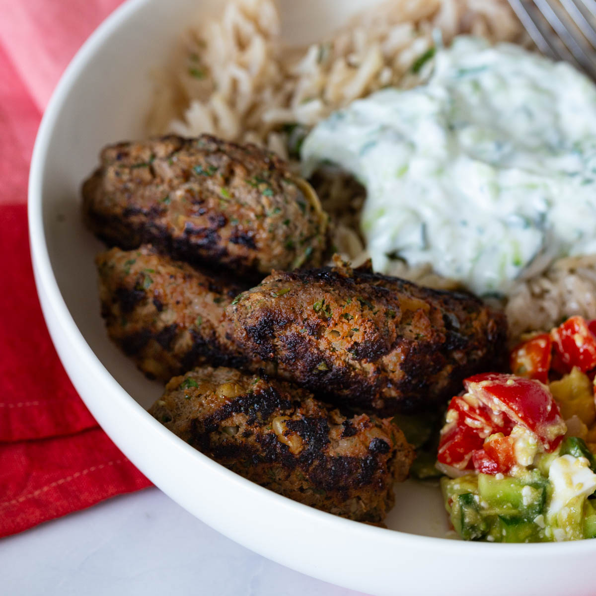 A Greek kofta kebabs with rice on a white plate.