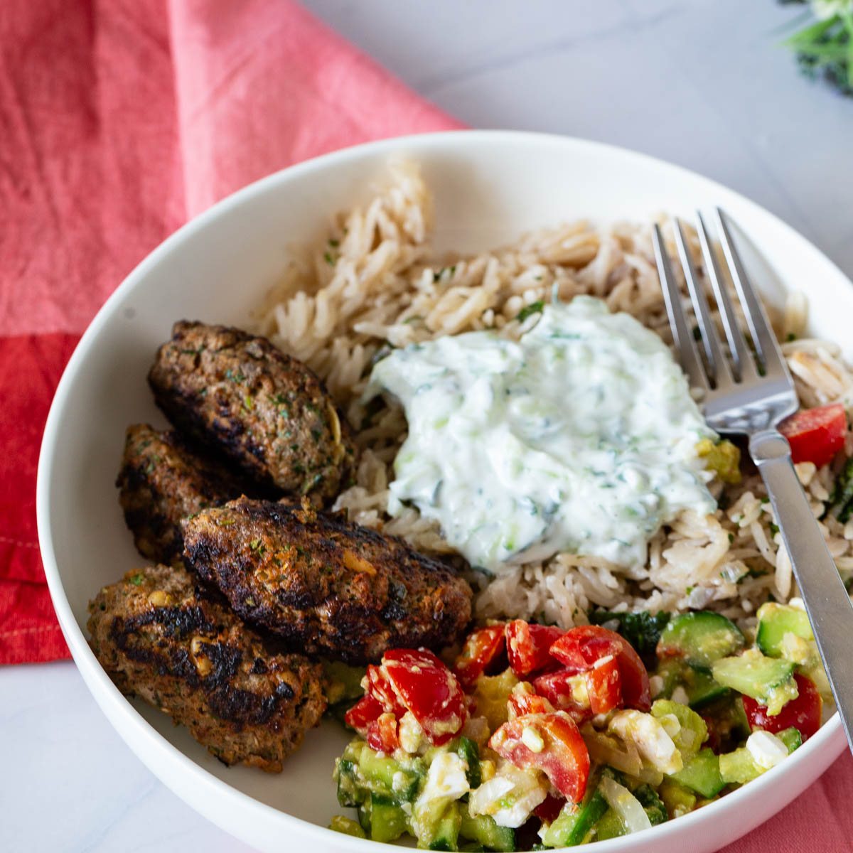 A white plate with beef and lamb Greek kofta kebabs.