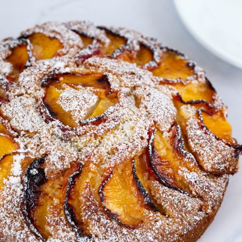 Top view peach cake dusted with powdered sugar.