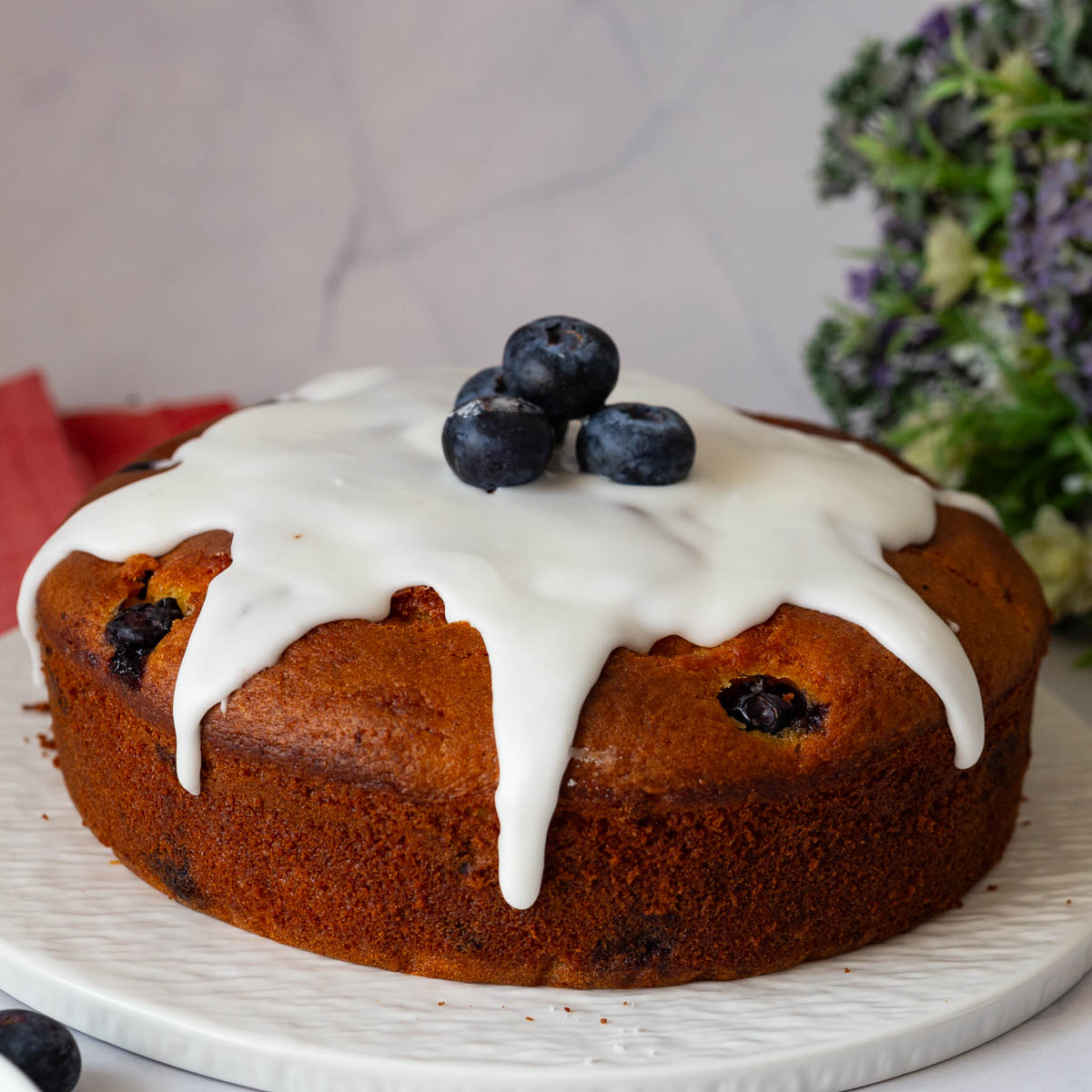 A blueberry cake with sugar glaze and fresh blueberries.