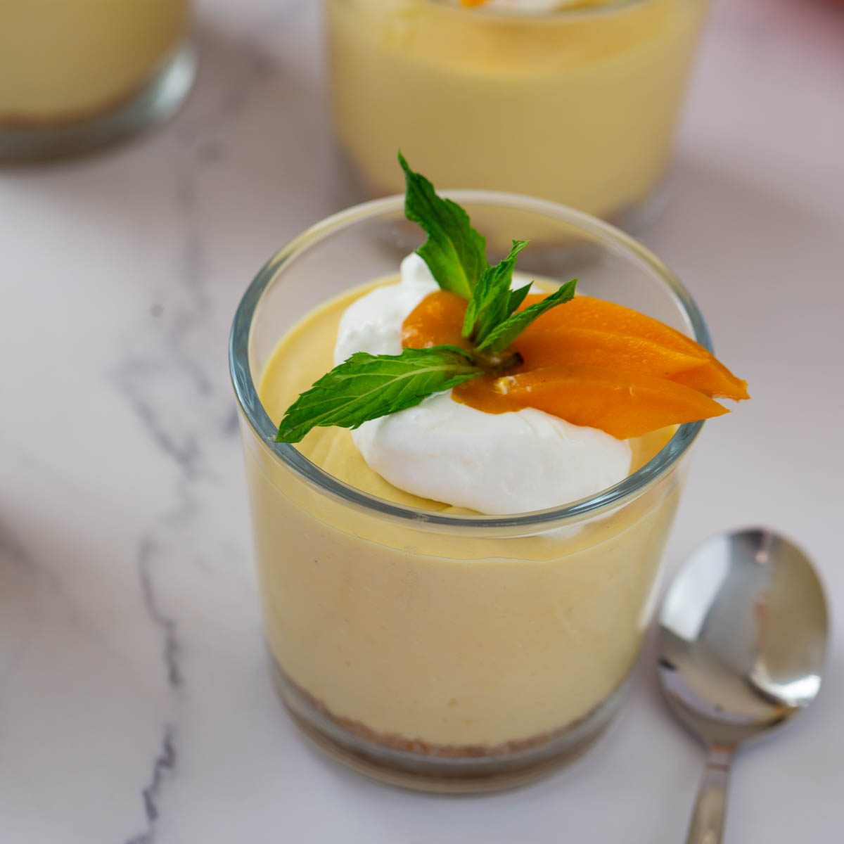 A mini cup with mango cheesecake.