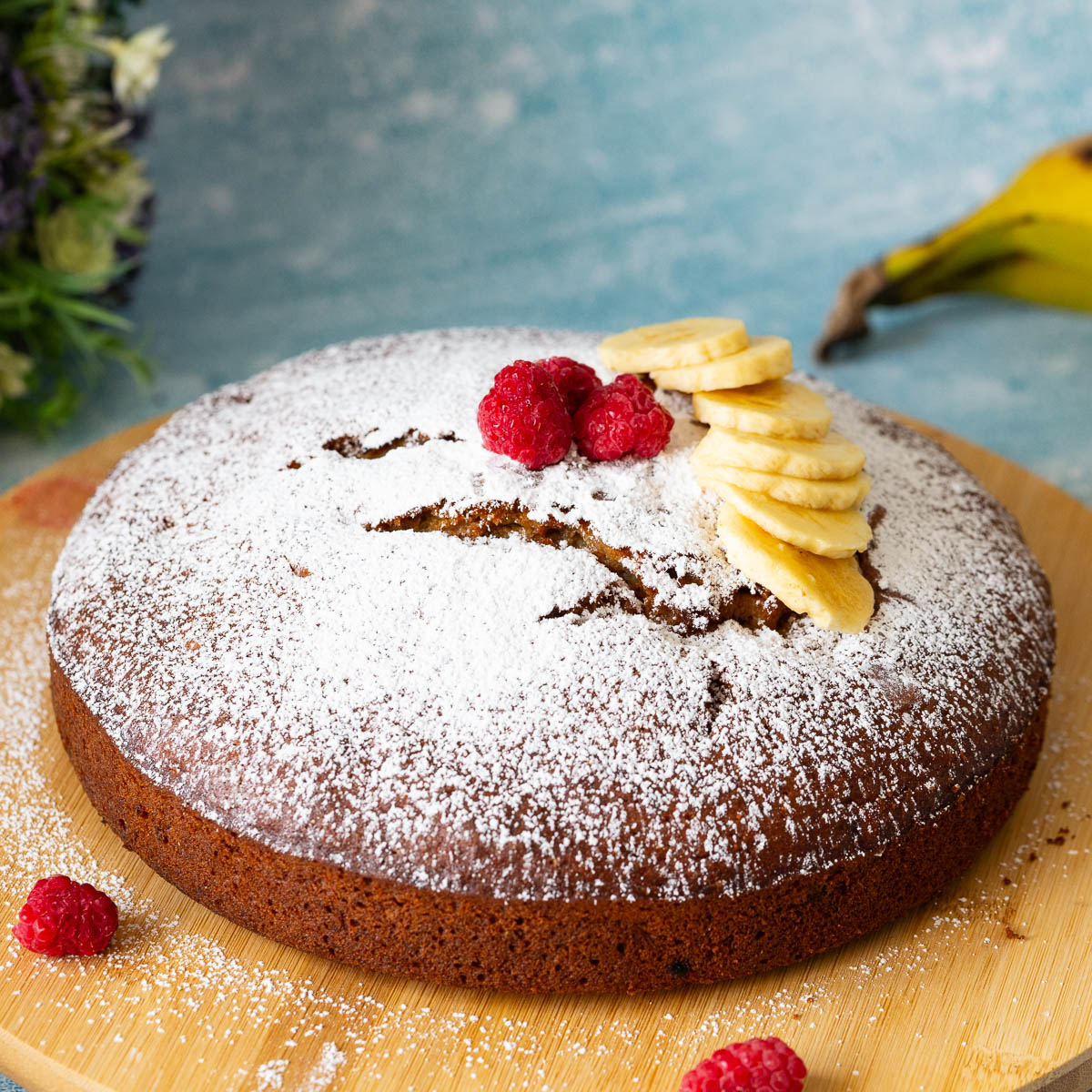 A cake dusted with powdered sugar on the cake stand.
