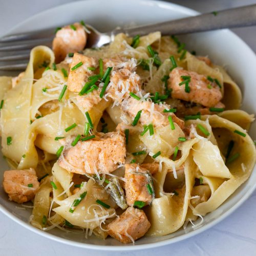 A plate with pasta in brown butter sauce with salmon.
