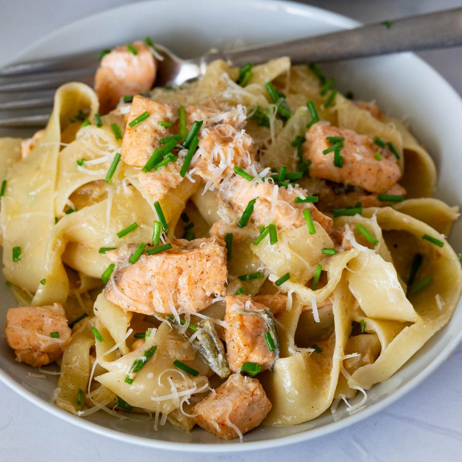 A plate with pasta in brown butter sauce with salmon.