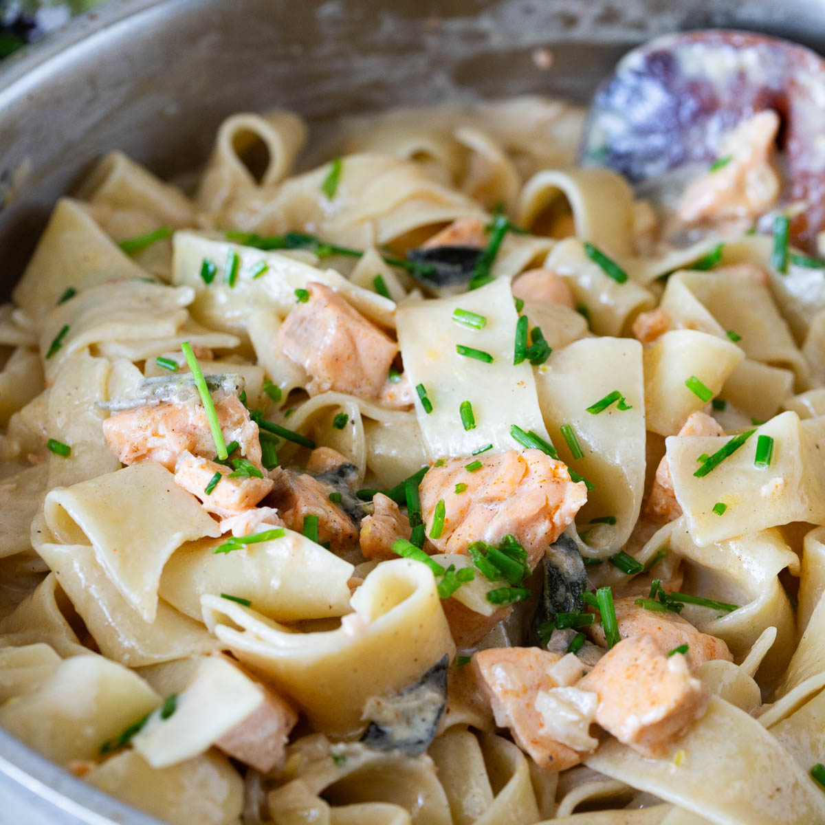 A skillet with salmon in brown butter sauce pasta.