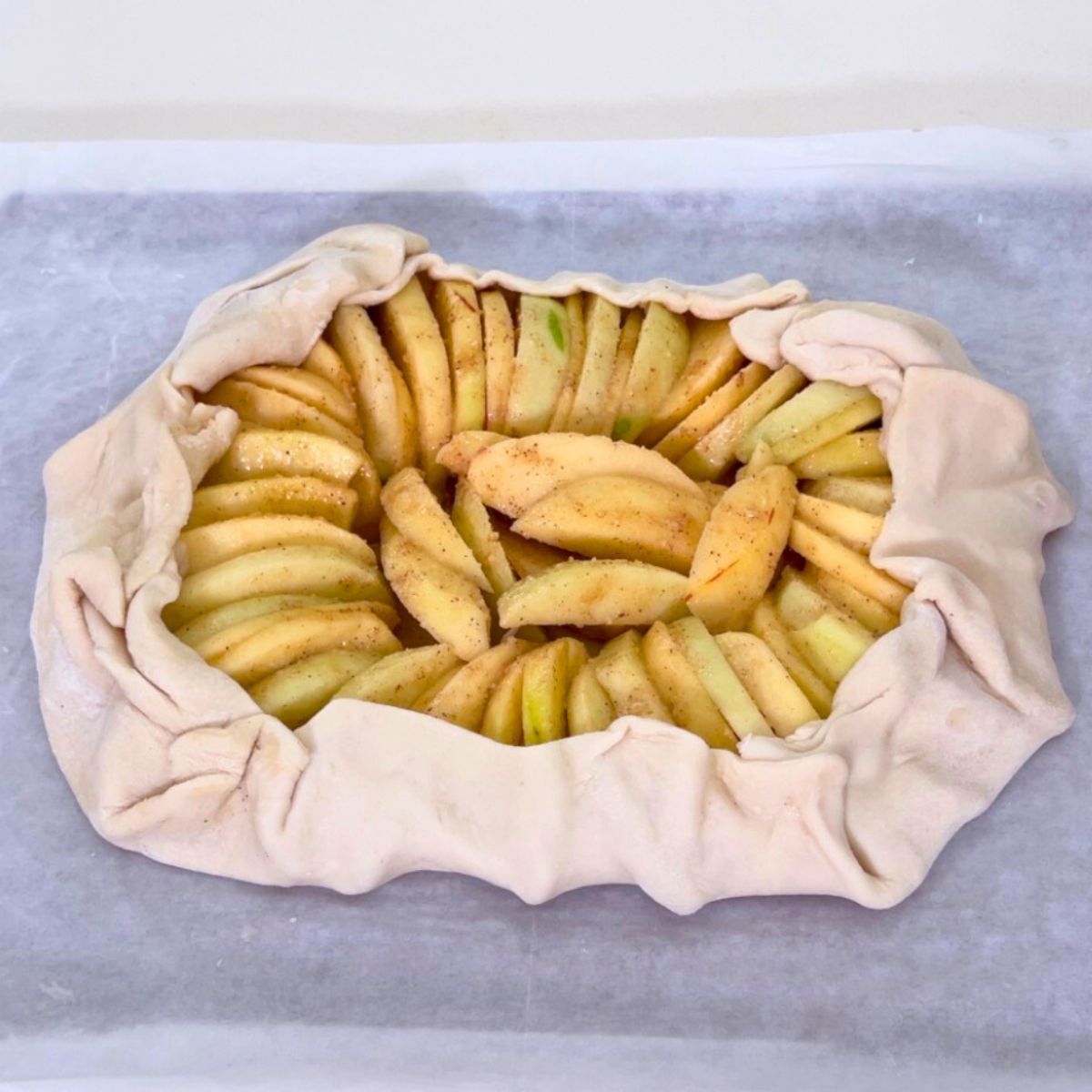 An unbaked apple galette on the baking tray.