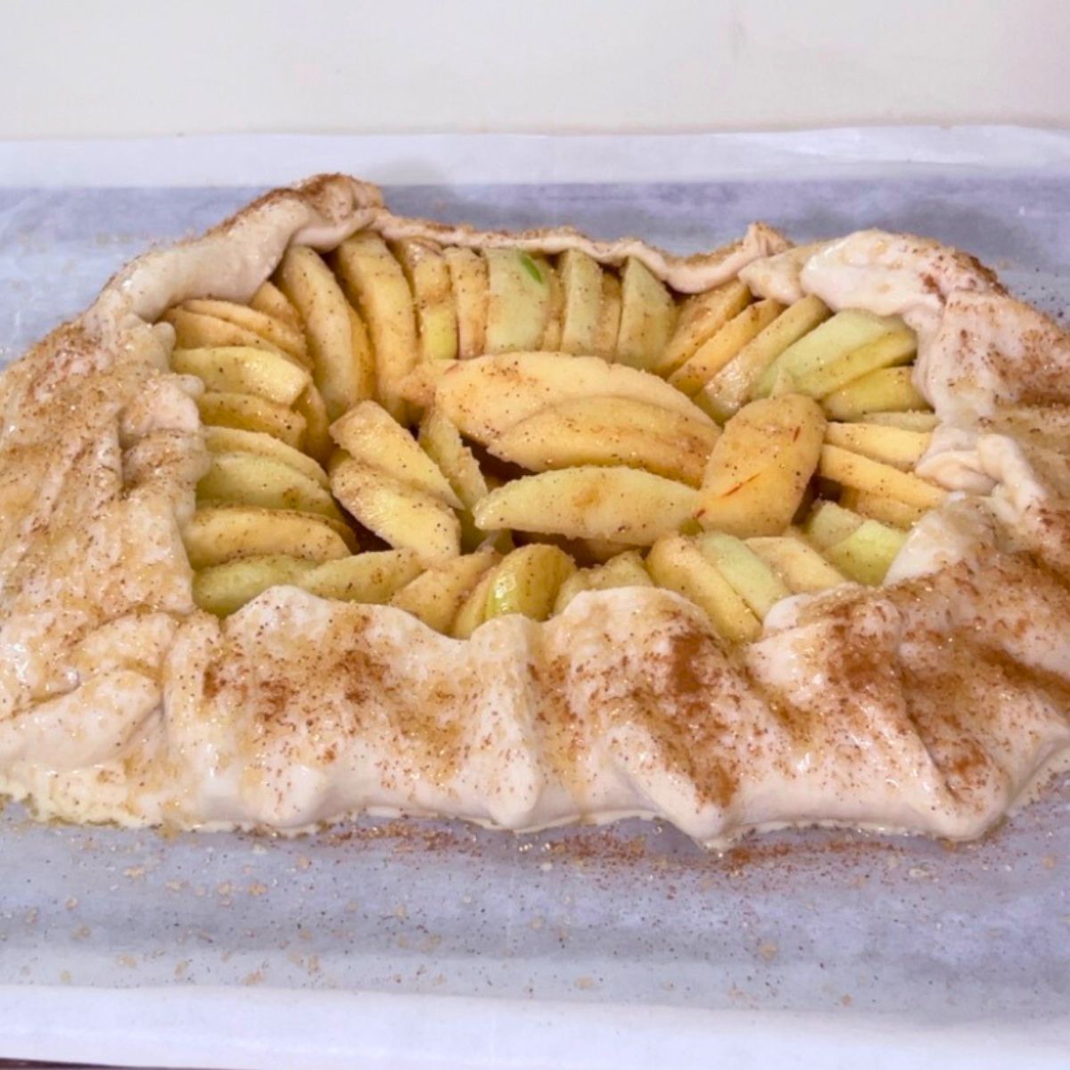 A baking tray with apple galette with cinnamon sugar.